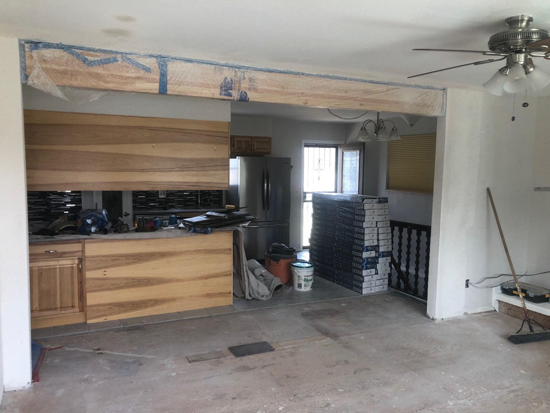 New wood header beam spanning the opening, still wrapped
