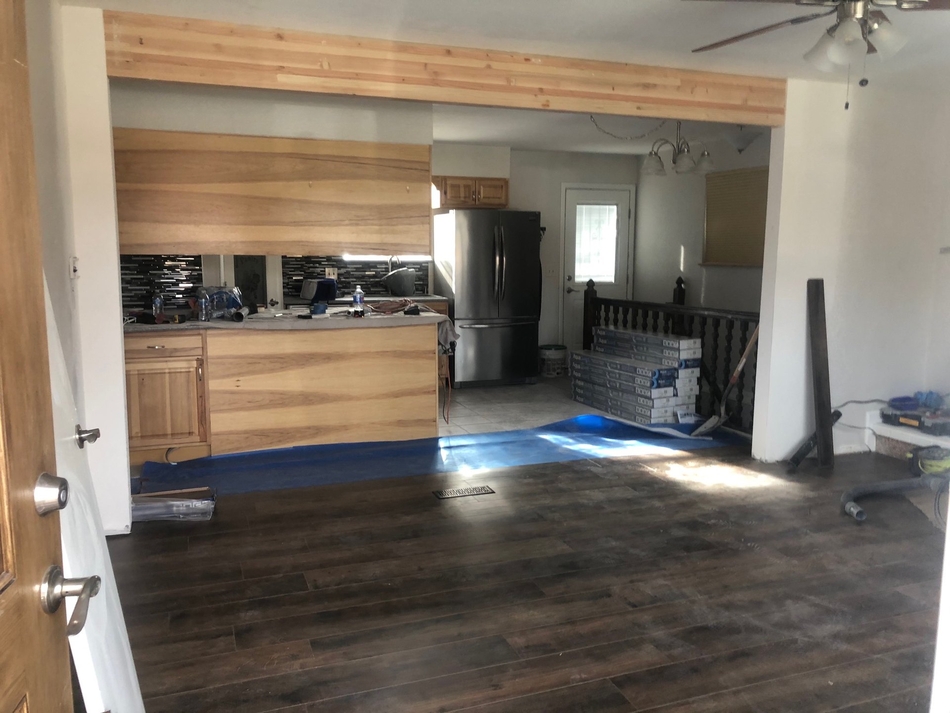 New plank flooring going in under the beam, mosaic kitchen still in the back