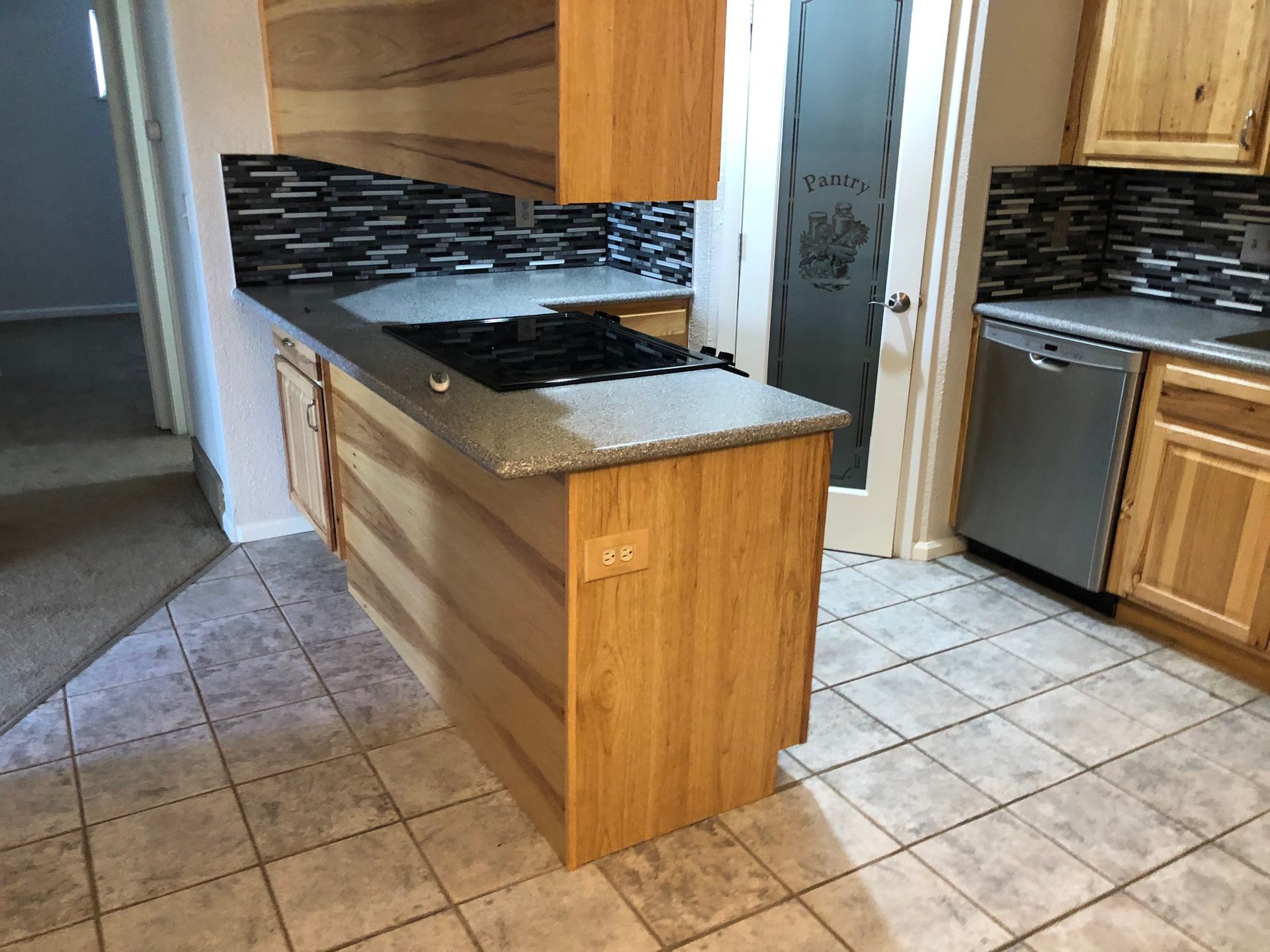 Finished kitchen with wood-grain cabinets and mosaic backsplash