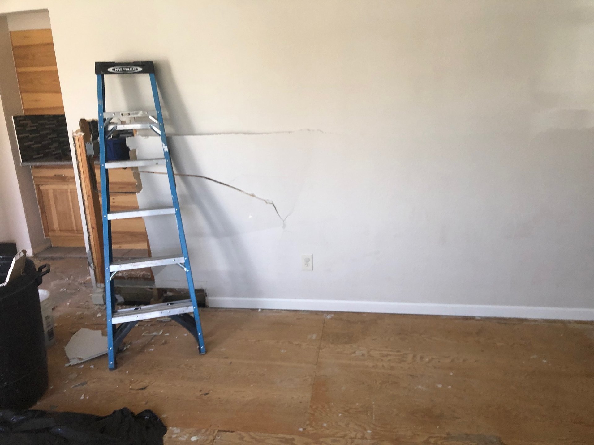 Living room wall cracked and opened during demo, ladder on the subfloor