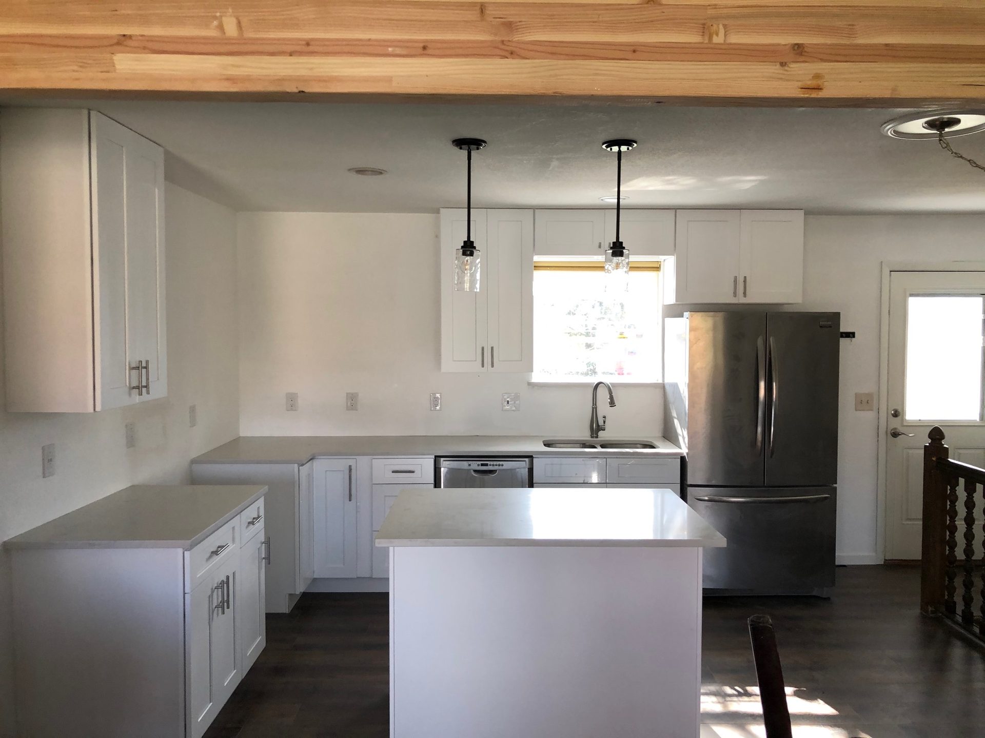 Open-concept kitchen with white cabinets and a wood beam